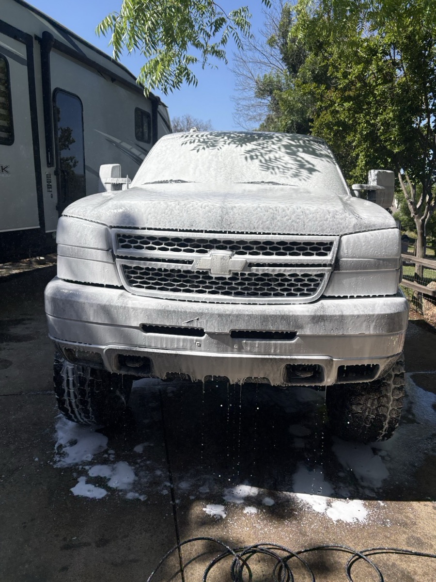 Chevy Silverado 2500HD covered in thick white foam during a pre-wash